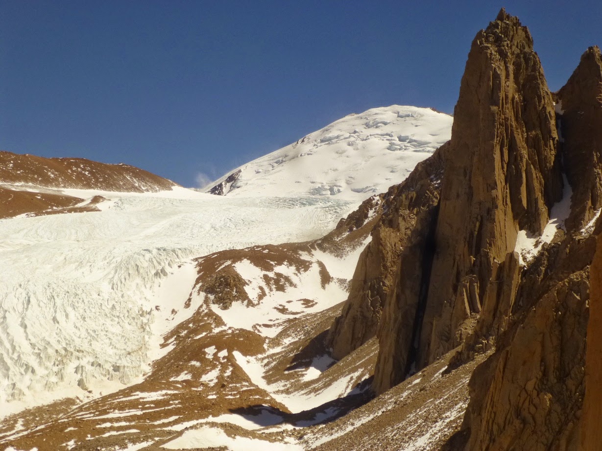 Glaciar y cumbre nevada junto a agujas rocosas afiladas bajo cielo despejado, de ambienteSCs alpino